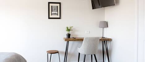 A small, modern room with a desk, chair, and a television mounted on the wall.
