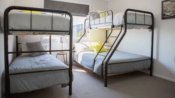 A room with two bunk beds, a small table, and a window with a view of buildings.