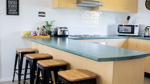 A kitchen with a central island, wooden stools, a microwave, and a toaster.