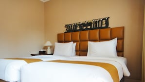 A hotel room with a large bed, a nightstand with a lamp, and a decorative headboard.