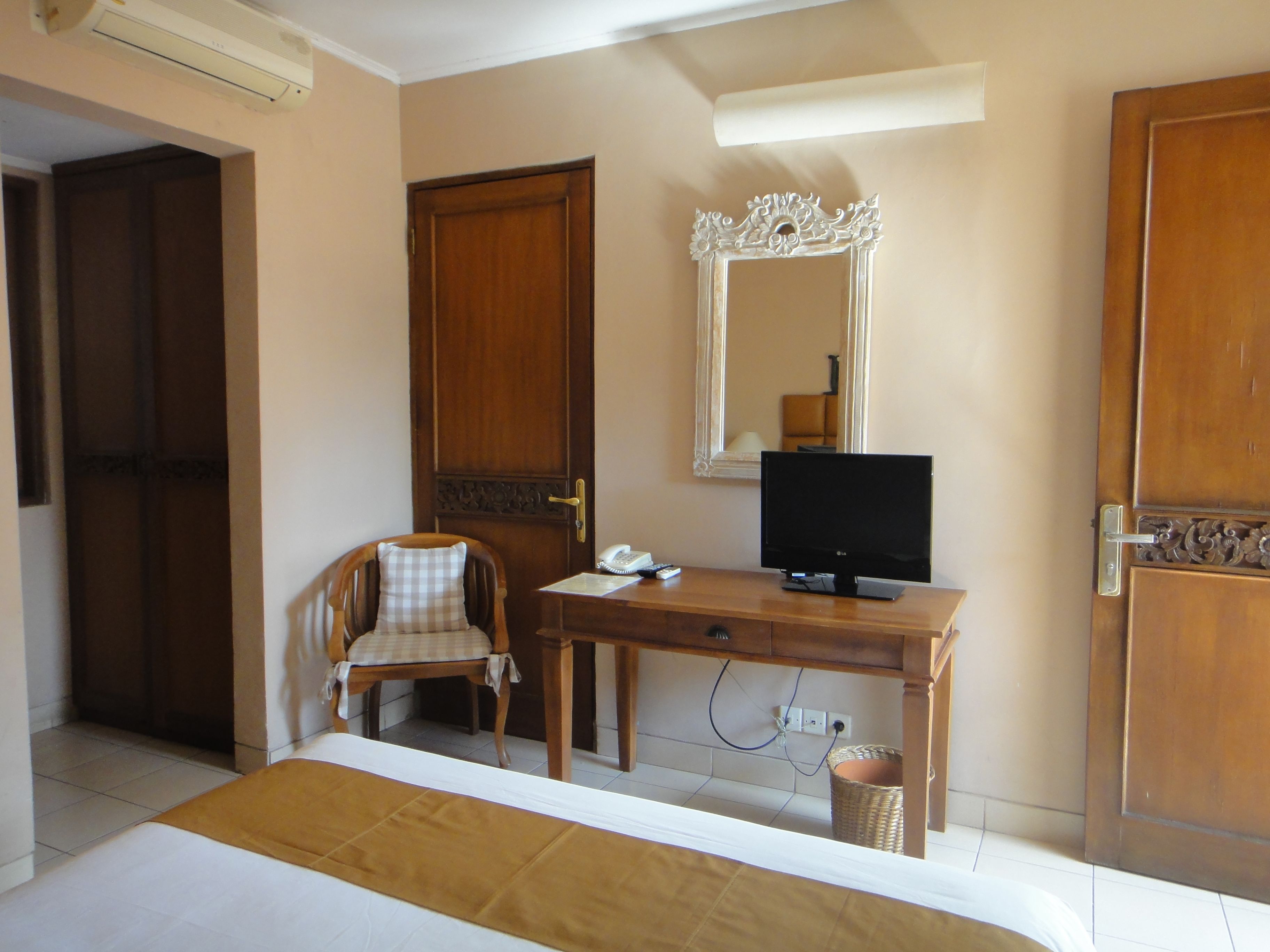 A bedroom with a bed, a desk with a television, a chair, and a wardrobe.