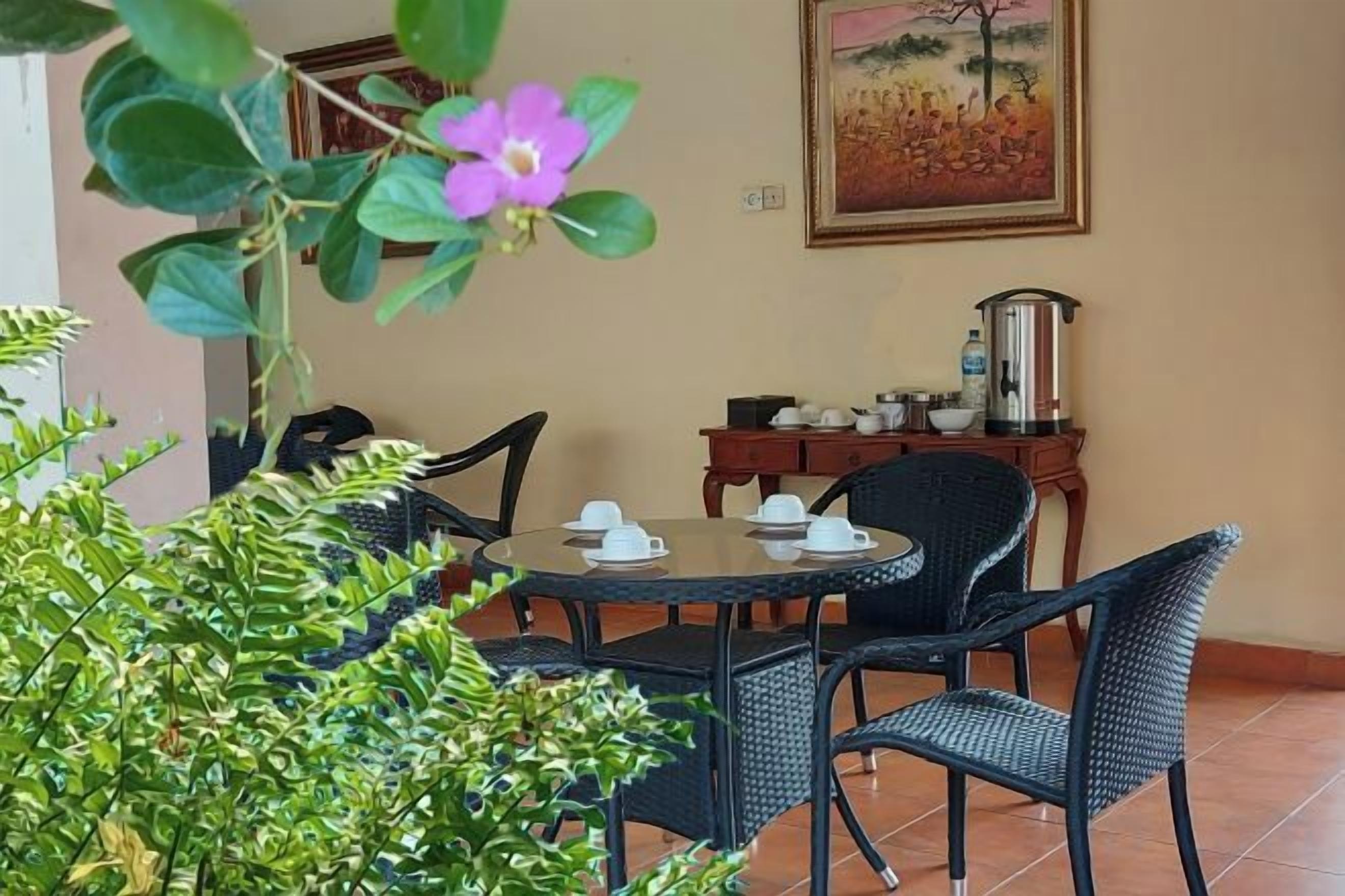 A dining area with a round table, chairs, and a coffee pot on a side table.