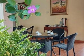 Un coin repas avec une table ronde, des chaises et une cafetière posée sur une petite table d’appoint.