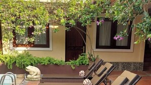 A poolside area with lounge chairs, a stone frog sculpture, and lush greenery.