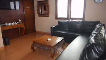 A living room with a black leather sofa, a wooden coffee table, a wooden cabinet, a mirror, and a clock on the wall.