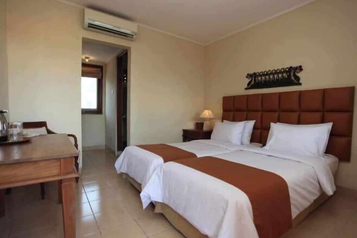 Habitación de hotel con cama doble, escritorio de madera, mesita de noche y un adorno en la pared.