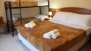 Ein Hotelzimmer mit einem Etagenbett, einem Einzelbett und einem Nachttisch mit Lampe.