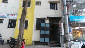 Un edificio con fachada amarilla, una verja negra y una escalera que conduce a la entrada.