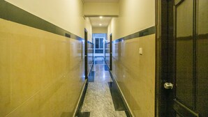 Un pasillo con suelo de mármol, una puerta a la derecha y vista hacia otra habitación al final.