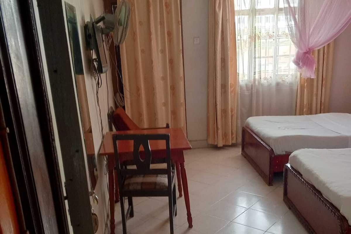 Een kamer met een bed, een stoel, een tafel en een raam met gordijnen.