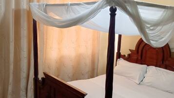 A four-poster bed with a canopy, wooden headboard, and white bedding.