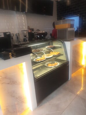 Un espace buffet avec un présentoir en verre contenant divers aliments.
