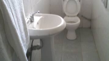 Un baño con lavamanos, inodoro y una toalla colgada en la pared.