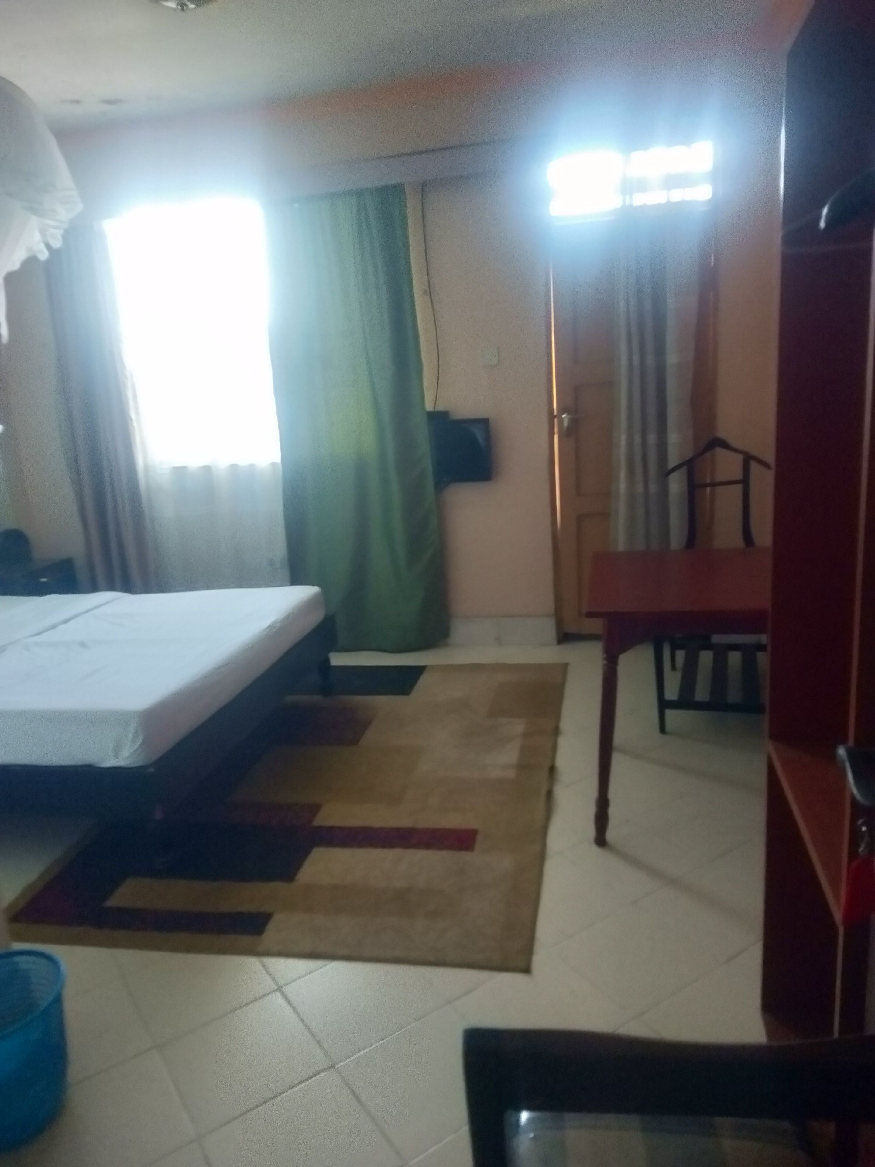 A hotel room with a bed, a desk, a chair, and a television.