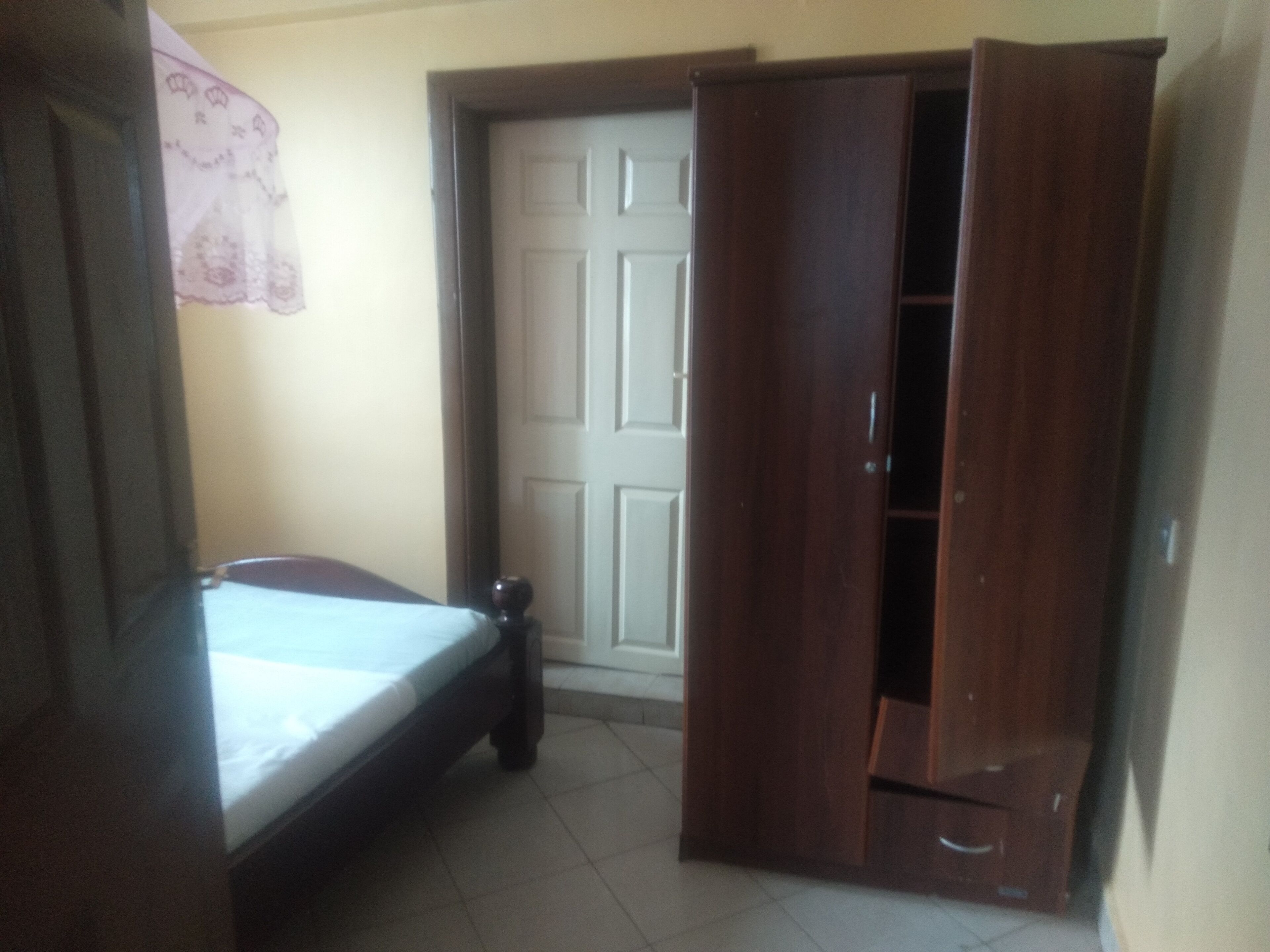 A bedroom with a bed, a wardrobe, and a door.