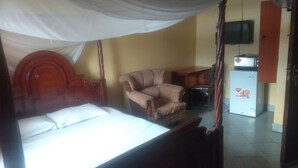 Une chambre à coucher comprenant un lit, une chaise, un téléviseur et un réfrigérateur.