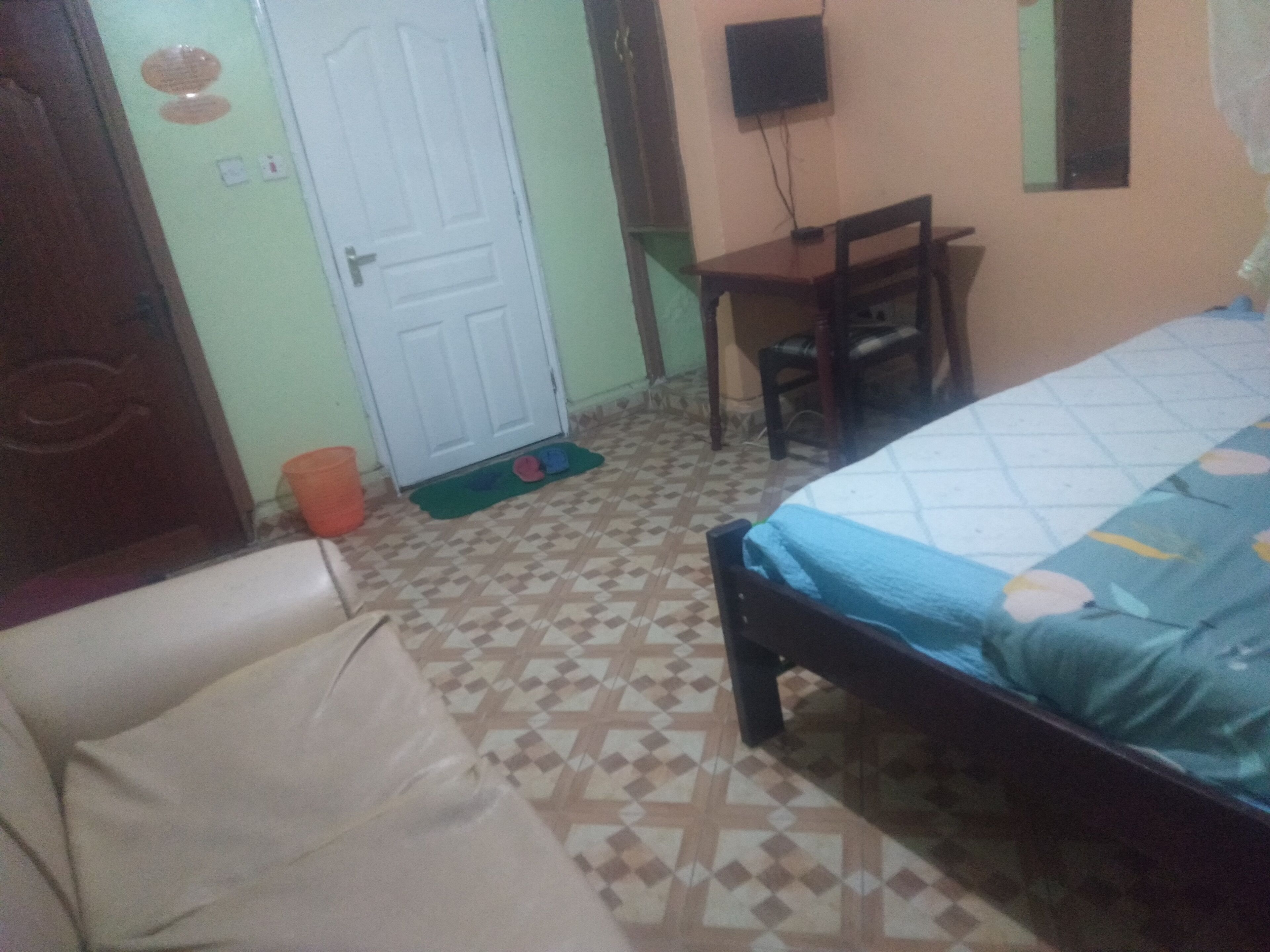 A room with a bed, a chair, a desk, and a door.