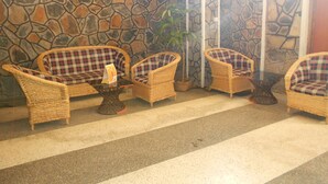 Un espace détente avec des fauteuils en osier et une table, le tout installé devant un mur en pierre.