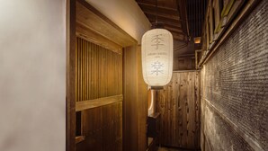 Un pasillo estrecho con puertas de madera y un farol colgante.