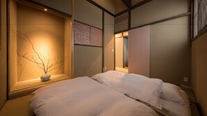 Una habitación de hotel con una cama, un ventanal decorado con una rama y un espejo montado en la pared.
