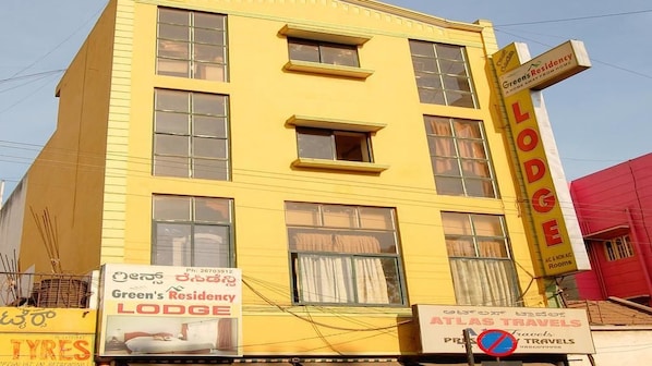 A yellow building with multiple windows and a sign for Green's Residency Lodge. - Green's Residency (Bengaluru)