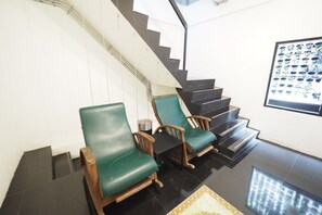 A staircase with green cushioned chairs and a framed plant display. - Zent & Bao Hostel (Bangkok)