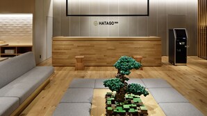 A reception area with a wooden reception desk, a digital kiosk, and a seating area with a small tree sculpture. - HATAGO INN Shizuoka Yoshida IC (Shimada)