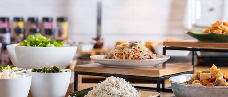 A dining table with various dishes, including rice, salad, and noodles.