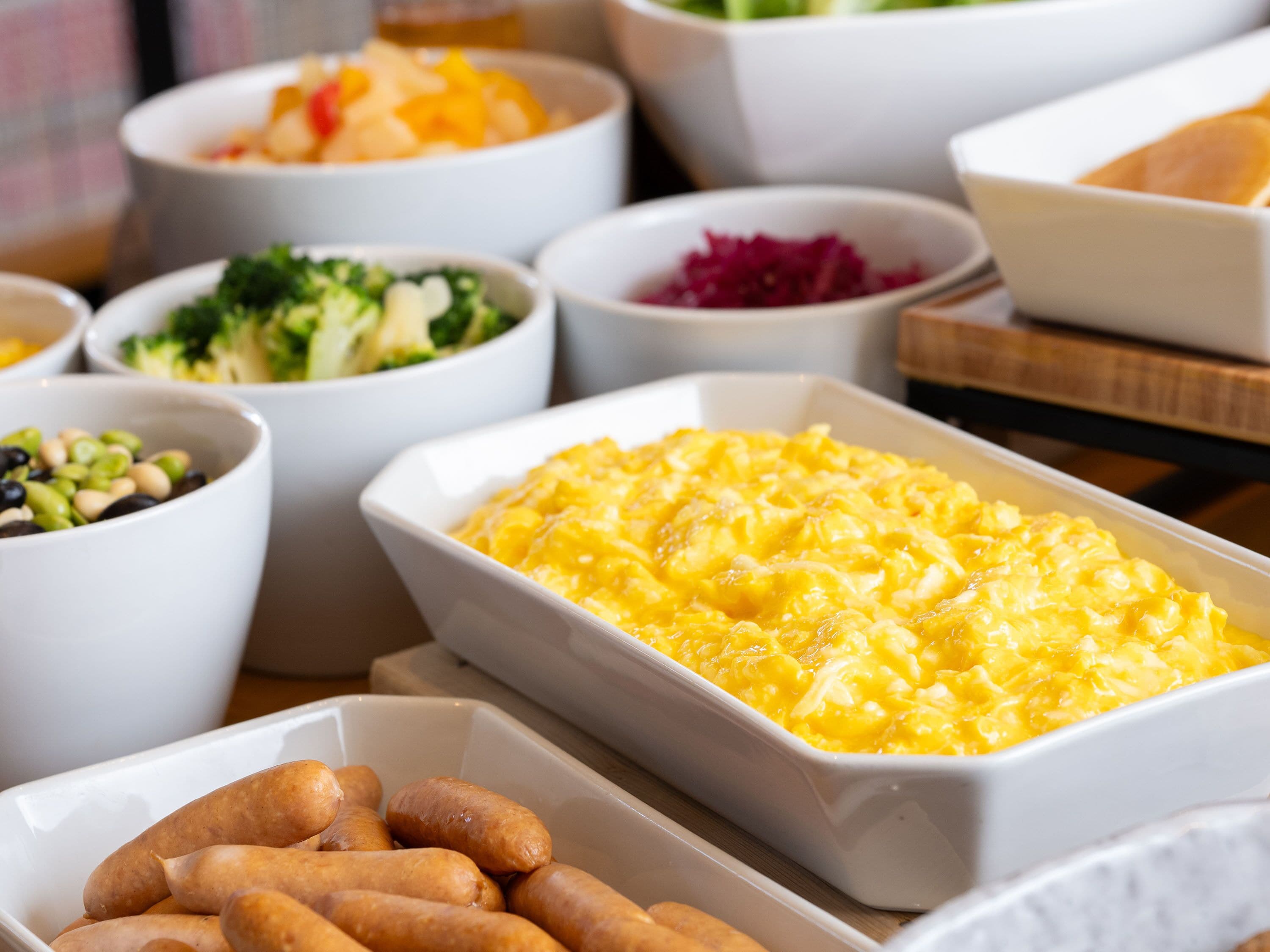Buffet com diversos pratos, incluindo macarrão com queijo, legumes e salsichas.