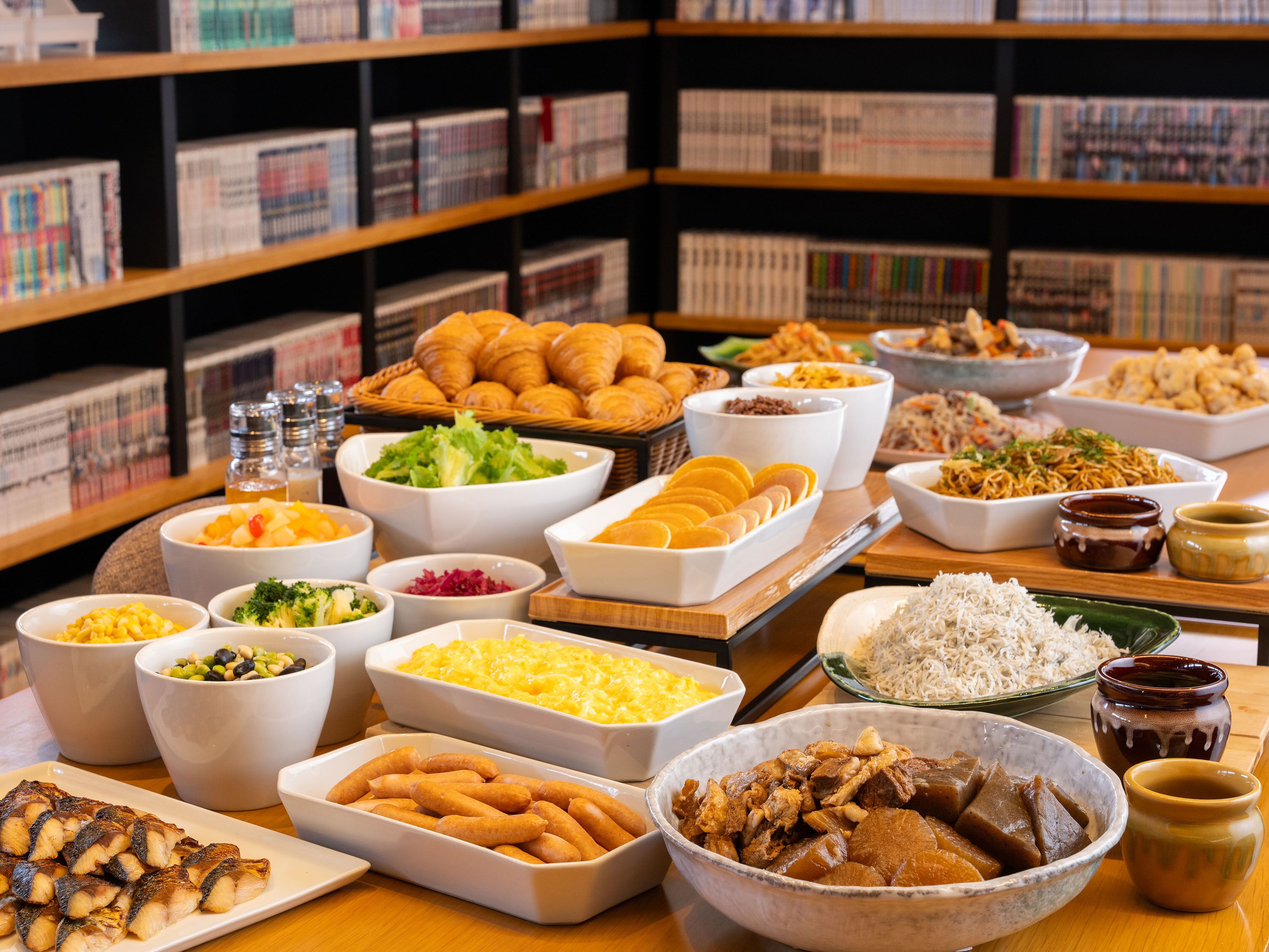 Ein Buffet mit verschiedenen Speisen und einem Bücherregal im Hintergrund.