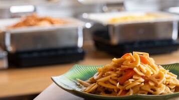 A close-up of a dish with pasta and vegetables on a green plate.