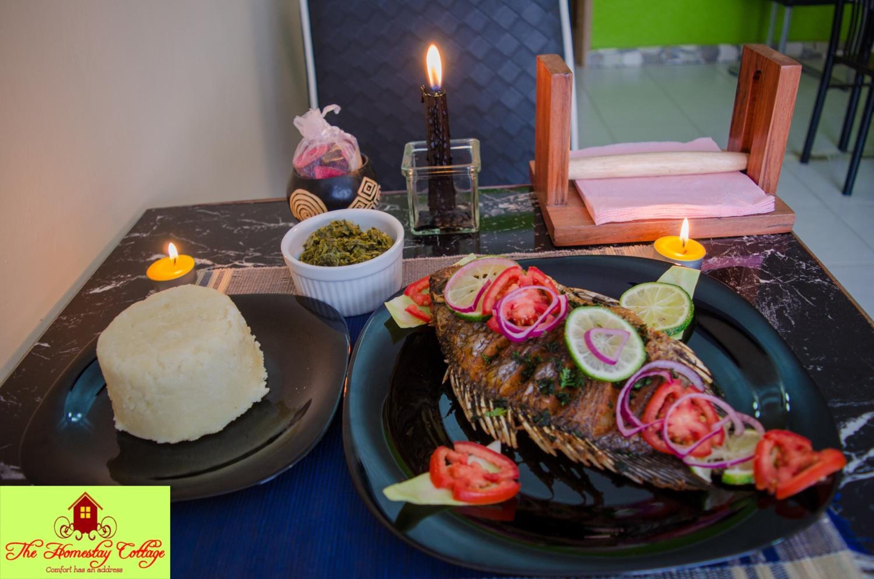 A table with a fish dish, rice, and candles.