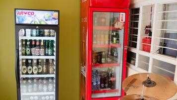 Two beverage vending machines, one with ARVCO branding and the other with Coca-Cola branding, next to a drum set.