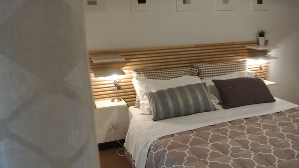 A neatly made bed with a patterned bedspread, a wooden headboard, and bedside lamps. - B&B Via dei Templi (Agrigento)
