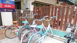 A row of colorful bicycles parked in front of a building with a sign for Vietnam Airlines and Air Asia. - Lucky Backpacker Hostel (Vientiane)