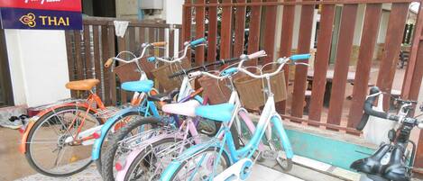 A row of colorful bicycles parked in front of a building with a sign for Vietnam Airlines and Air Asia.