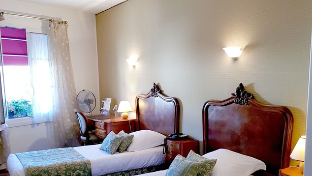 A hotel room with two beds, a chair, a desk, and a window with curtains. - Hostellerie du Grand Sully (Sully-sur-Loire)