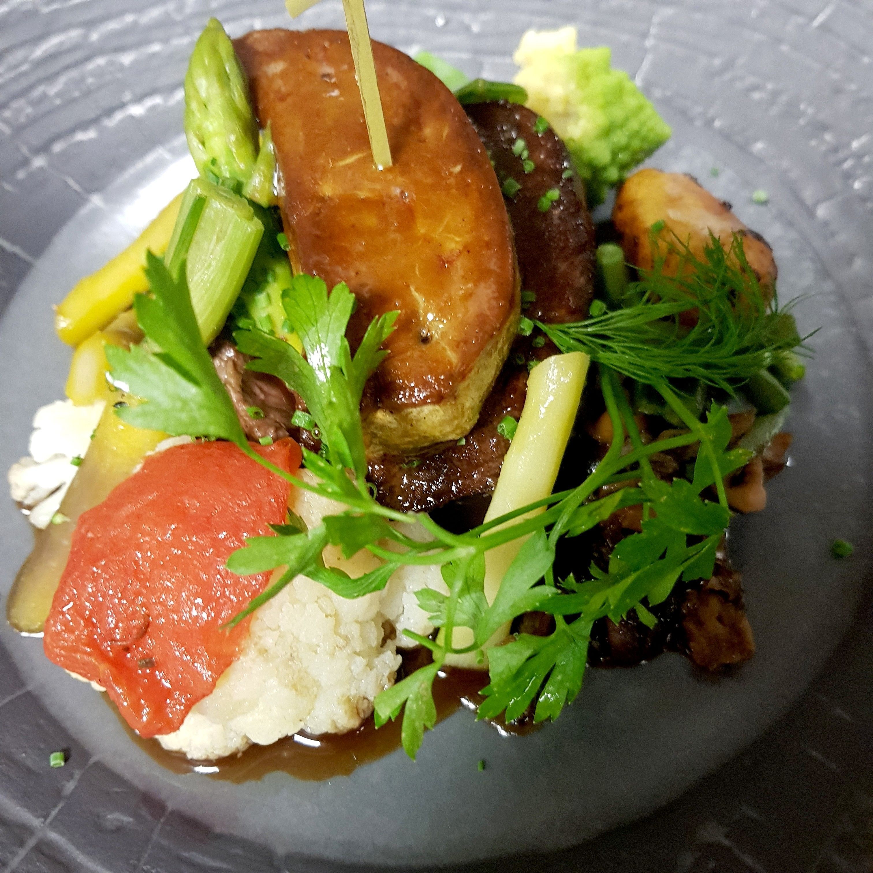 A plate of food with various vegetables and a piece of meat.