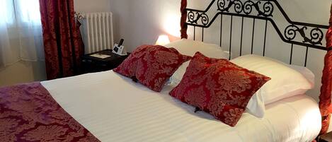 A bed with red and white bedding, a bedside table with a lamp, and a radiator.
