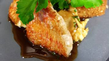 A plated dish with breaded items, sauce, and garnishes.