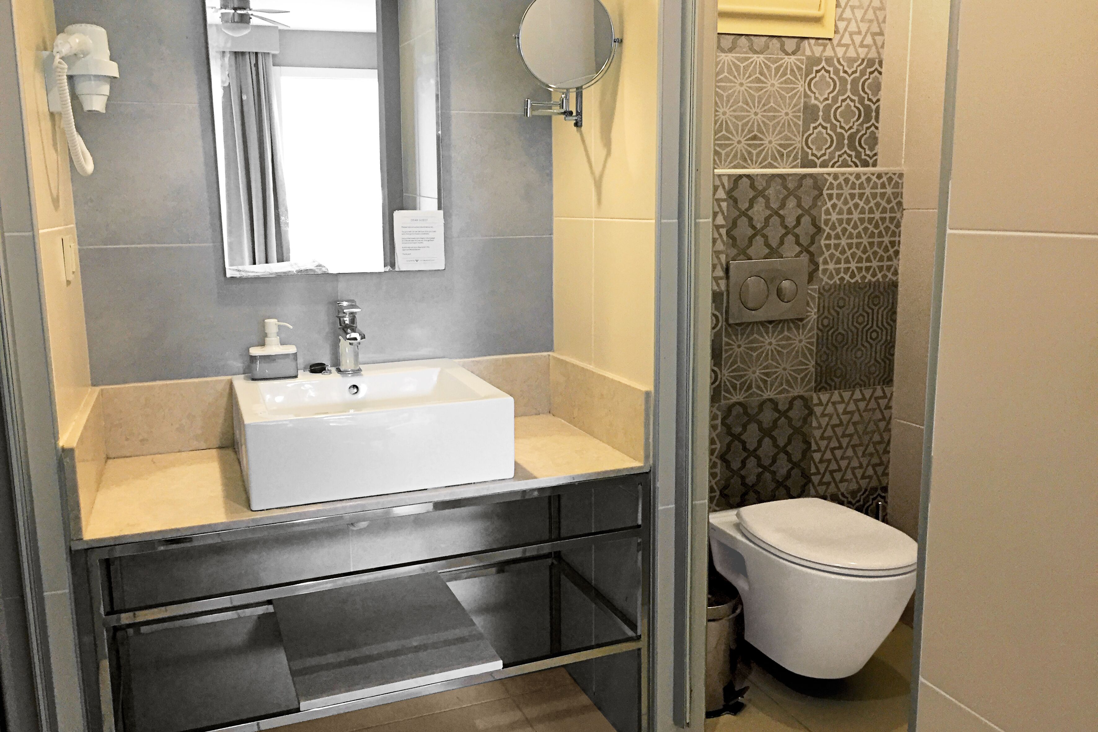 Un baño con lavamanos, espejo y retrete blanco.