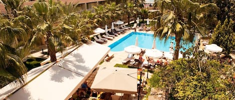 Een buitenzwembad, parasols bij het zwembad en ligstoelen