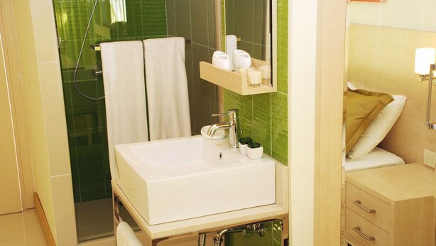 A bathroom with a white sink, a mirror, a towel rack, a shower, and a bedside table with a lamp. - Sunprime Dogan Side Beach - Adults Only (Manavgat)