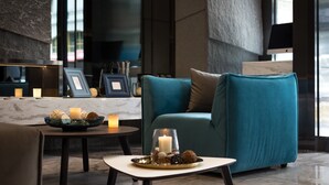 Un moderno vestíbulo con un sofá azul aguamarina, una mesita redonda con velas y un cuenco decorativo.