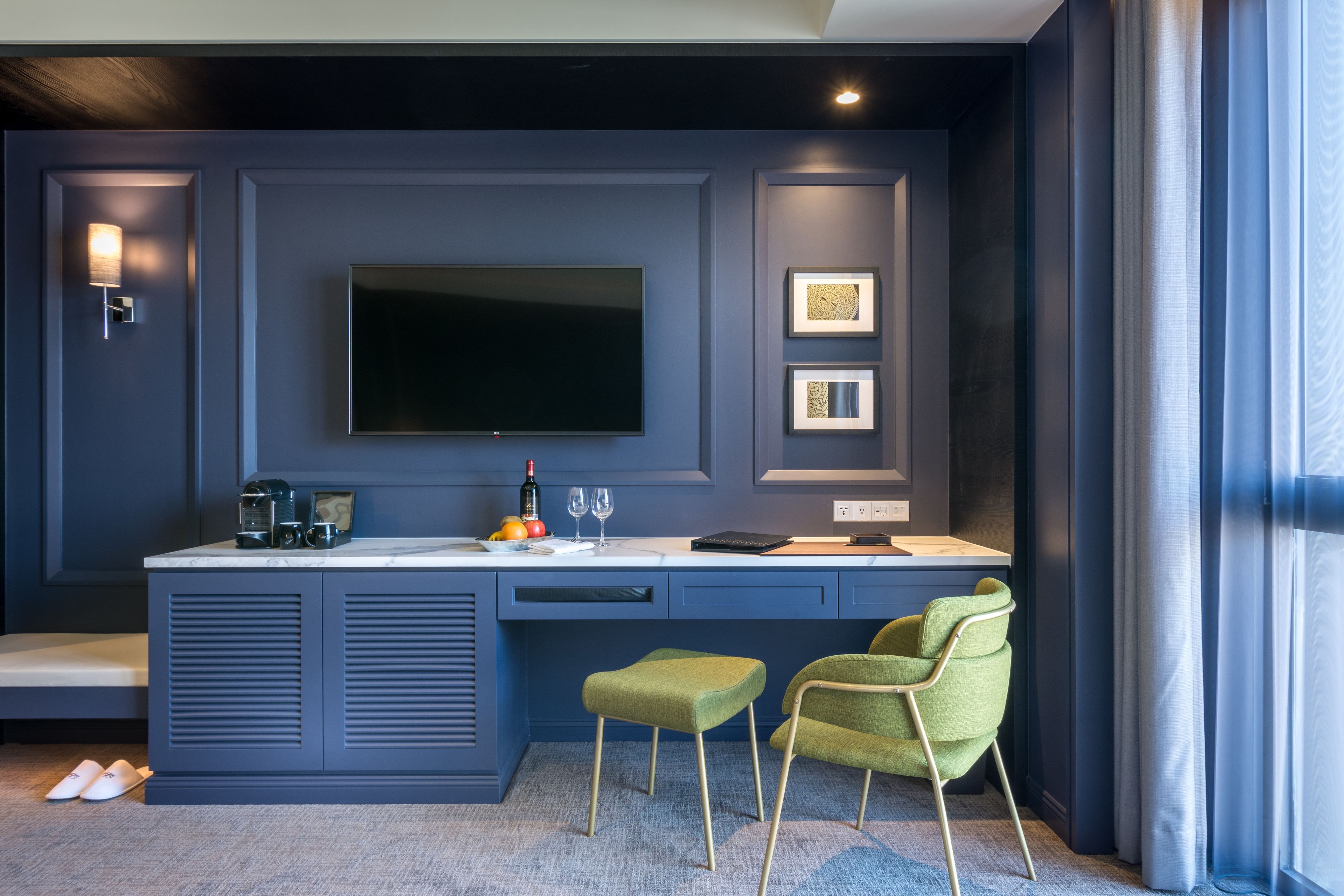 A modern kitchen with a flat-screen TV, two framed pictures, and a coffee machine.