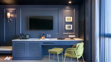 A modern kitchen with a flat-screen TV, two framed pictures, and a coffee machine.