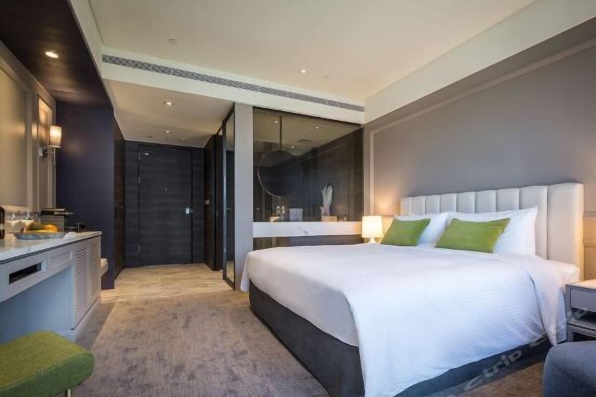 Una habitación de hotel moderna con una cama grande, un escritorio y un espejo.