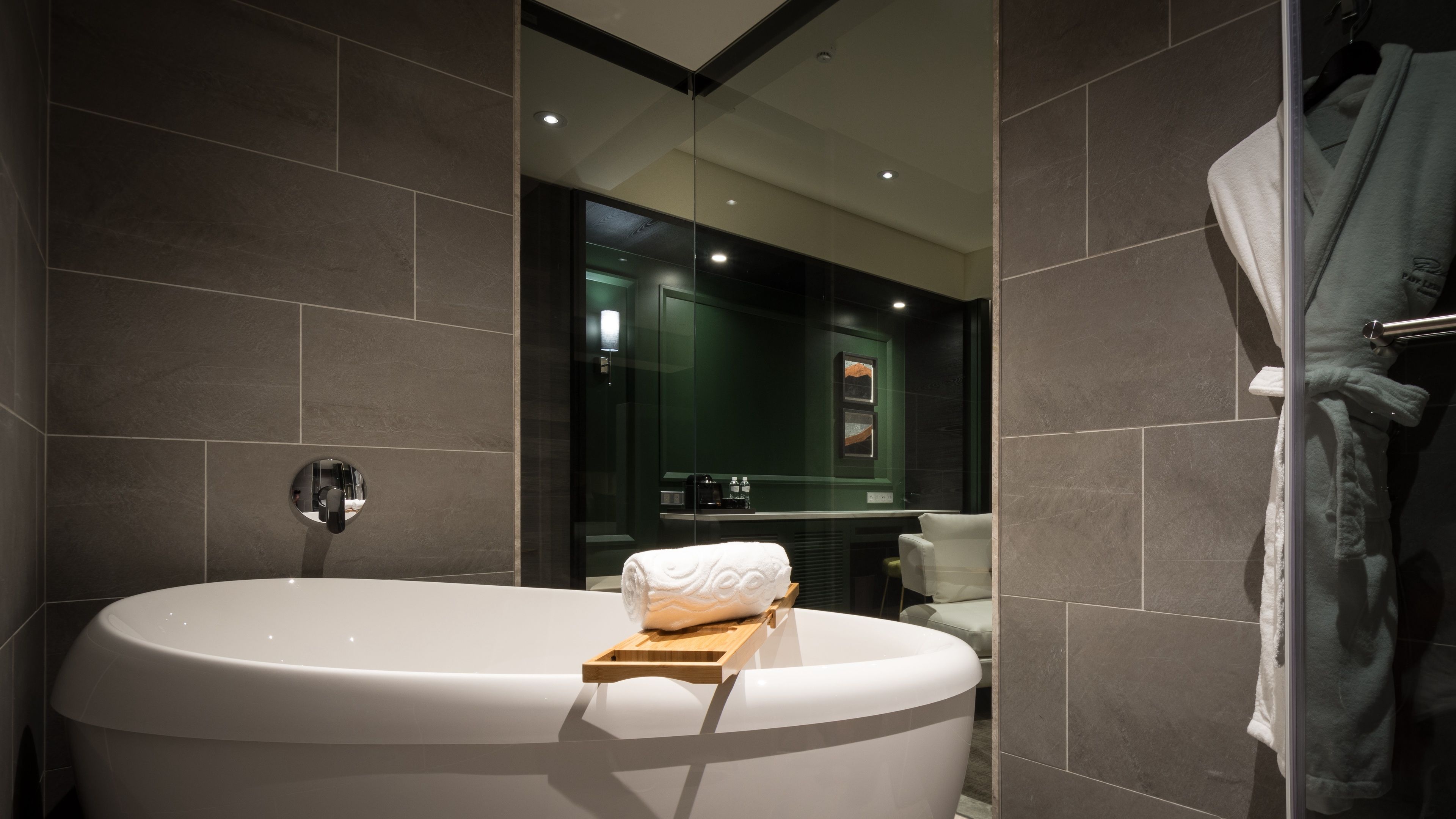 A modern bathroom with a freestanding bathtub, a towel rack, and a glass shower enclosure.