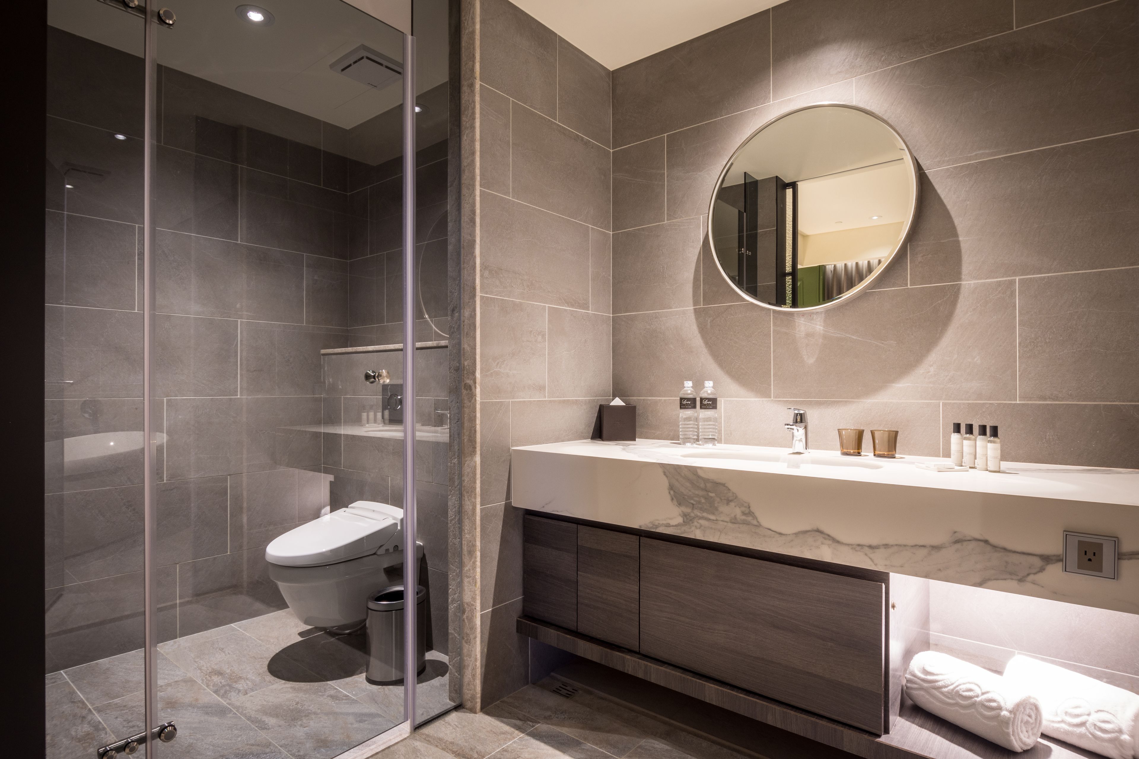 Une salle de bain moderne avec une douche à parois de verre, des toilettes, un meuble-lavabo avec un miroir et un porte-serviettes.