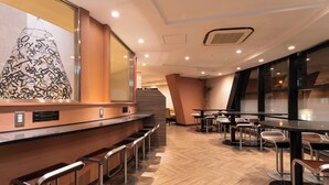 Un espace bar moderne avec un plancher en bois, des tabourets de bar en métal et une grande œuvre d’art abstraite accrochée au mur.